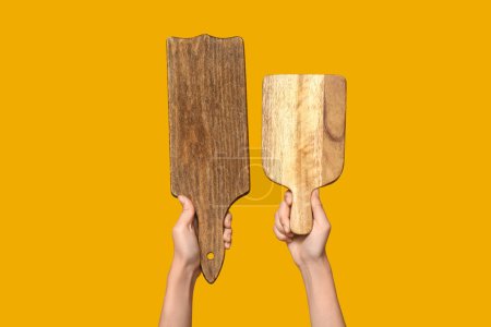 Foto de Manos femeninas con tablas de cortar de madera sobre fondo amarillo - Imagen libre de derechos