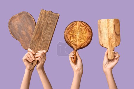 Foto de Manos femeninas con tablas de cortar de madera sobre fondo lila - Imagen libre de derechos