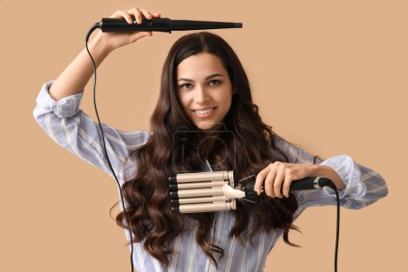 Téléchargez les photos : Beautiful young woman with different curling irons on beige background - en image libre de droit