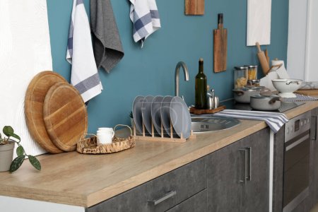 Foto de Wooden kitchen counters with cutting boards, plate rack, sink, electric stove and utensils - Imagen libre de derechos