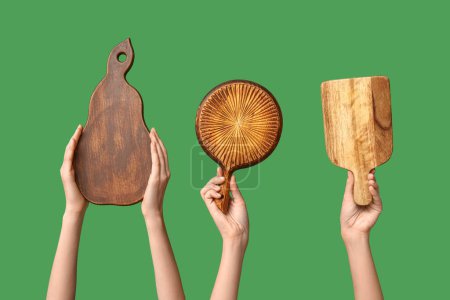 Foto de Manos femeninas con tablas de cortar de madera sobre fondo verde - Imagen libre de derechos