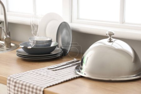 Téléchargez les photos : Comptoir de cuisine avec vaisselle propre et cloche près de la fenêtre - en image libre de droit