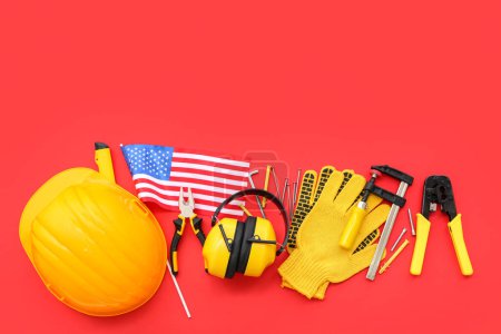 Foto de Composición con diferentes herramientas, equipo de protección y bandera de EE.UU. sobre fondo rojo. Fiesta del Día del Trabajo - Imagen libre de derechos