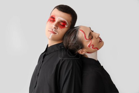 Téléchargez les photos : Jeune couple avec des visages peints sur fond clair - en image libre de droit