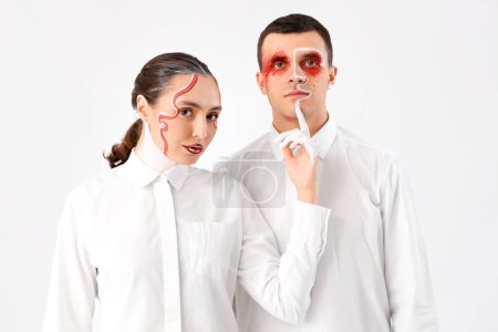 Téléchargez les photos : Jeune couple avec des visages peints sur fond blanc - en image libre de droit
