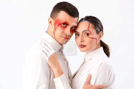 Téléchargez les photos : Jeune couple avec des visages peints étreignant sur fond blanc - en image libre de droit