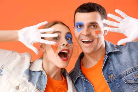 Téléchargez les photos : Jeune couple avec des visages peints sur fond orange, gros plan - en image libre de droit