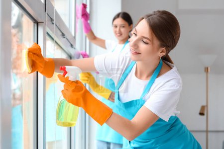 Photo for Female janitor cleaning window in room - Royalty Free Image