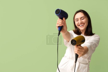 Photo for Beautiful young woman with hair dryers on green background - Royalty Free Image