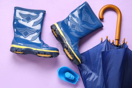 Foto de Botas de goma y paraguas azules sobre fondo lila - Imagen libre de derechos