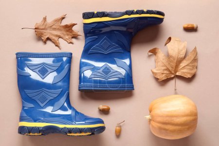 Foto de Botas de goma azules con calabaza, bellotas y hojas de otoño sobre fondo marrón - Imagen libre de derechos