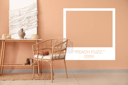 Foto de Elegante interior doméstico con sillón de ratán y mesa cerca de la pared de pelusa de melocotón - Imagen libre de derechos