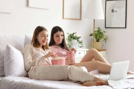 Foto de Amigas con palomitas de maíz viendo películas en el dormitorio - Imagen libre de derechos
