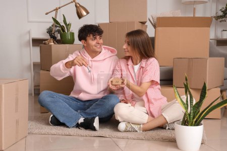 Téléchargez les photos : Jeune couple avec les clés et la figure de la maison dans leur nouvel appartement - en image libre de droit