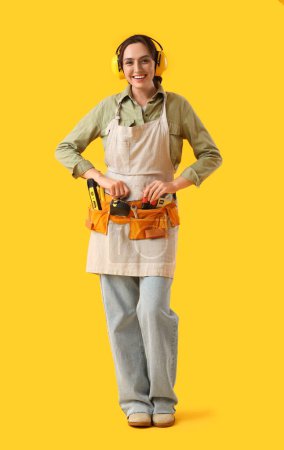 Foto de Trabajadora con bolsa de herramientas sobre fondo amarillo - Imagen libre de derechos