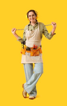 Foto de Trabajadora con bolsa de herramientas sobre fondo amarillo - Imagen libre de derechos
