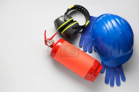 Foto de Extintor de incendios, protectores auditivos, guantes y casco sobre fondo gris - Imagen libre de derechos