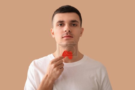 Photo for Young man with paper thyroid gland on beige background, closeup - Royalty Free Image