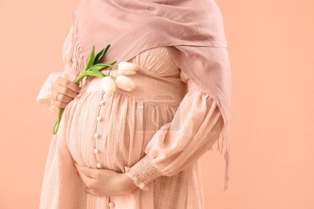 Foto de Mujer embarazada joven con tulipanes sobre fondo desnudo, primer plano - Imagen libre de derechos