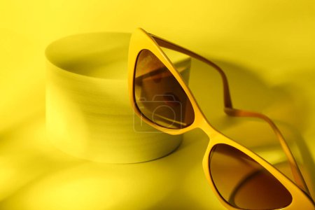 Téléchargez les photos : Podium avec des lunettes de soleil élégantes sur fond jaune - en image libre de droit