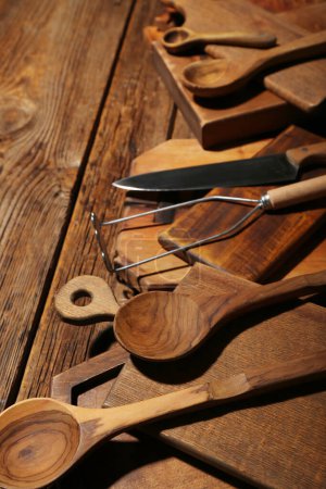 Foto de Diferentes tablas de cortar, machacador de papas, cucharas y cuchillo sobre fondo de madera - Imagen libre de derechos