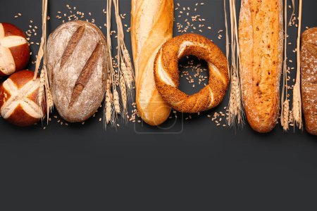 Photo for Different types of bread and wheat ears on black background - Royalty Free Image