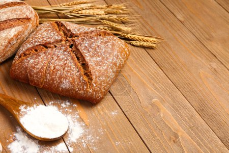 Photo for Loaf of fresh rye bread and wheat flour on wooden table - Royalty Free Image