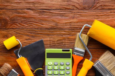 Calculator and painting tools on wooden background. Renovation budget concept