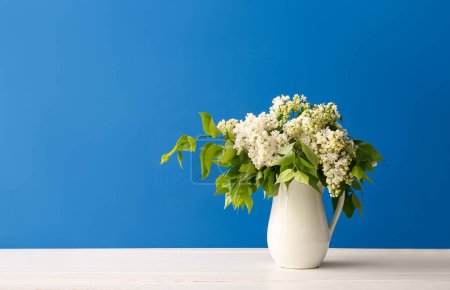 Foto de Jarrón de lilas blancas sobre mesa de madera cerca de la pared azul - Imagen libre de derechos