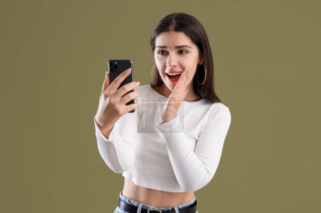 Téléchargez les photos : Jeune femme commérage avec téléphone portable sur fond vert - en image libre de droit