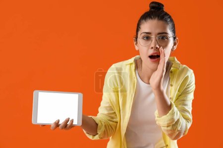 Téléchargez les photos : Jeune femme commérage avec ordinateur tablette sur fond orange - en image libre de droit