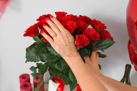 Foto de Manos femeninas con anillo de compromiso y ramo de rosas rojas, primer plano. Celebraciones del Día de San Valentín - Imagen libre de derechos
