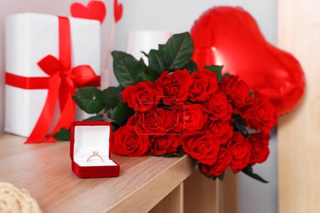 Foto de Caja con anillo de compromiso y ramo de hermosas rosas en la mesa, primer plano. Celebraciones del Día de San Valentín - Imagen libre de derechos