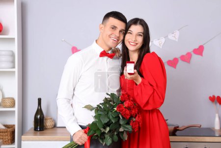 Photo for Young man with bouquet of roses proposing to his girlfriend in kitchen. Valentine's Day celebration - Royalty Free Image