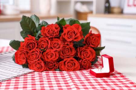 Foto de Caja con anillo de compromiso y ramo de rosas rojas en la mesa, primer plano. Celebración de San Valentín - Imagen libre de derechos