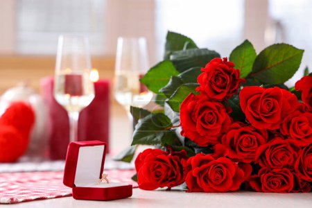 Foto de Caja con anillo de compromiso y ramo de rosas en la mesa, primer plano. Celebración de San Valentín - Imagen libre de derechos