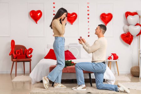 Foto de Joven proponiéndole matrimonio a su novia en el dormitorio. Celebración de San Valentín - Imagen libre de derechos