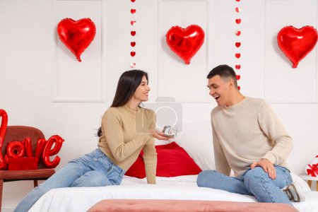 Foto de Joven proponiéndole matrimonio a su novia en el dormitorio. Celebración de San Valentín - Imagen libre de derechos