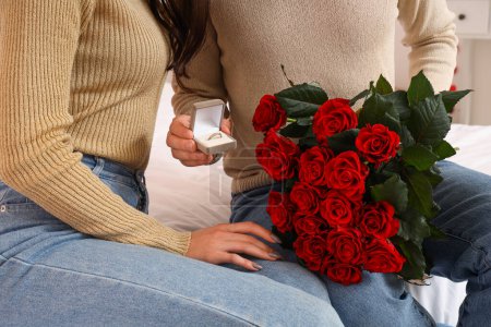 Foto de Pareja comprometida con ramo de rosas en casa, primer plano. Celebración de San Valentín - Imagen libre de derechos