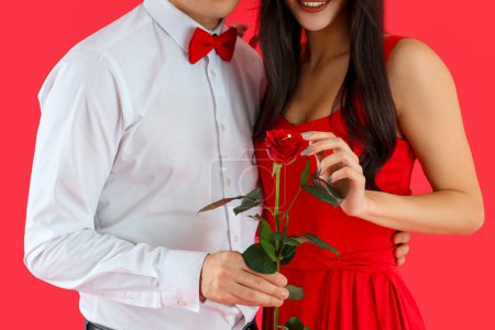 Foto de Pareja comprometida con anillo de boda en hermosa rosa sobre fondo rojo. Celebración de San Valentín - Imagen libre de derechos