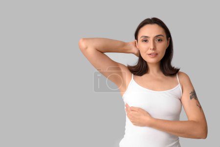 Young woman checking her breast on light background. Cancer awareness concept