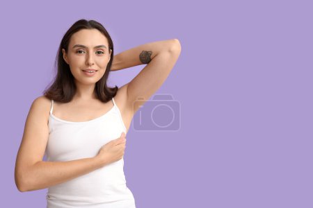 Foto de Mujer joven revisando su pecho sobre fondo lila. Concepto de concienciación - Imagen libre de derechos