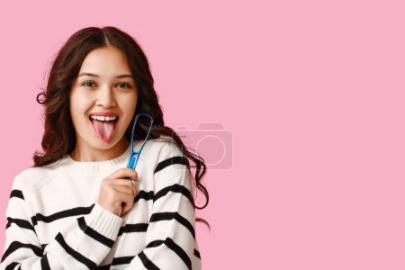 Téléchargez les photos : Jeune femme asiatique avec grattoir de langue sur fond rose - en image libre de droit