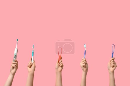 Téléchargez les photos : Mains féminines avec brosses à dents et grattoirs à langue sur fond rose - en image libre de droit