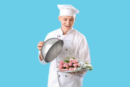 Téléchargez les photos : Chef masculin avec cloche et tulipes sur fond bleu. Célébration de la Journée internationale de la femme - en image libre de droit