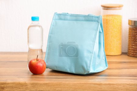 Foto de Bolsa de almuerzo con manzana y botella de agua en la mesa en la cocina - Imagen libre de derechos