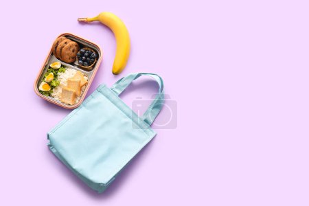 Foto de Bolsa, lonchera con deliciosa comida y plátano sobre fondo lila - Imagen libre de derechos
