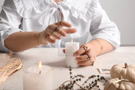 Hexe mit brennender Kerze am hellen Grunge-Tisch, Nahaufnahme