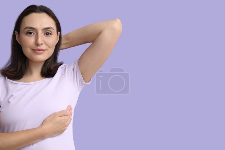 Mujer joven revisando su pecho sobre fondo lila. Concepto de concienciación
