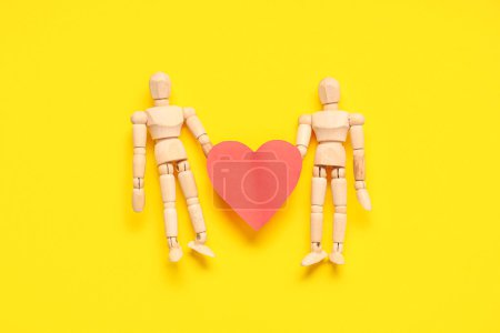 Téléchargez les photos : Mannequins en bois avec coeur en papier sur fond jaune. Fête de la Saint Valentin - en image libre de droit